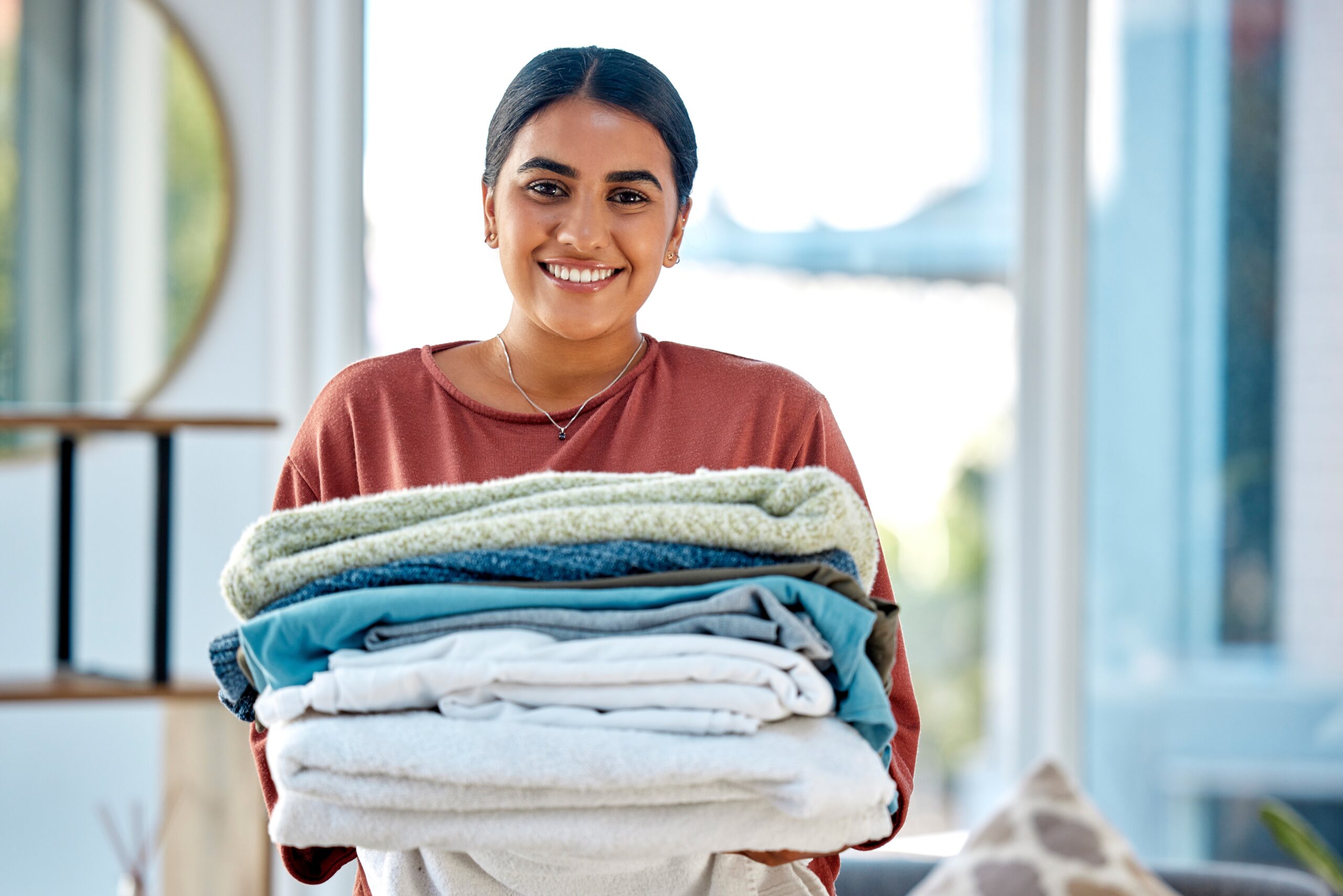 woman holding washed and folded laundry from dewy